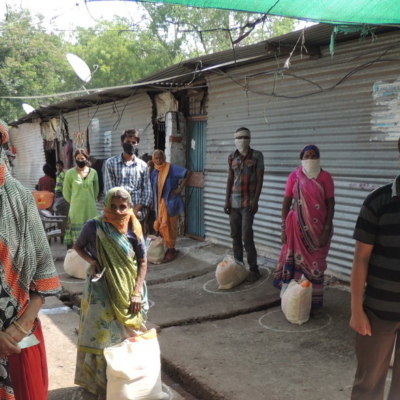 BewohnerInnen von einem Slum in Indien reihen sich auf für die Verteilung von Corona-Nothilfe-Paketen.